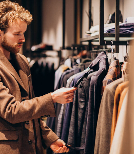 Young handsome man choosing cloth at shop
